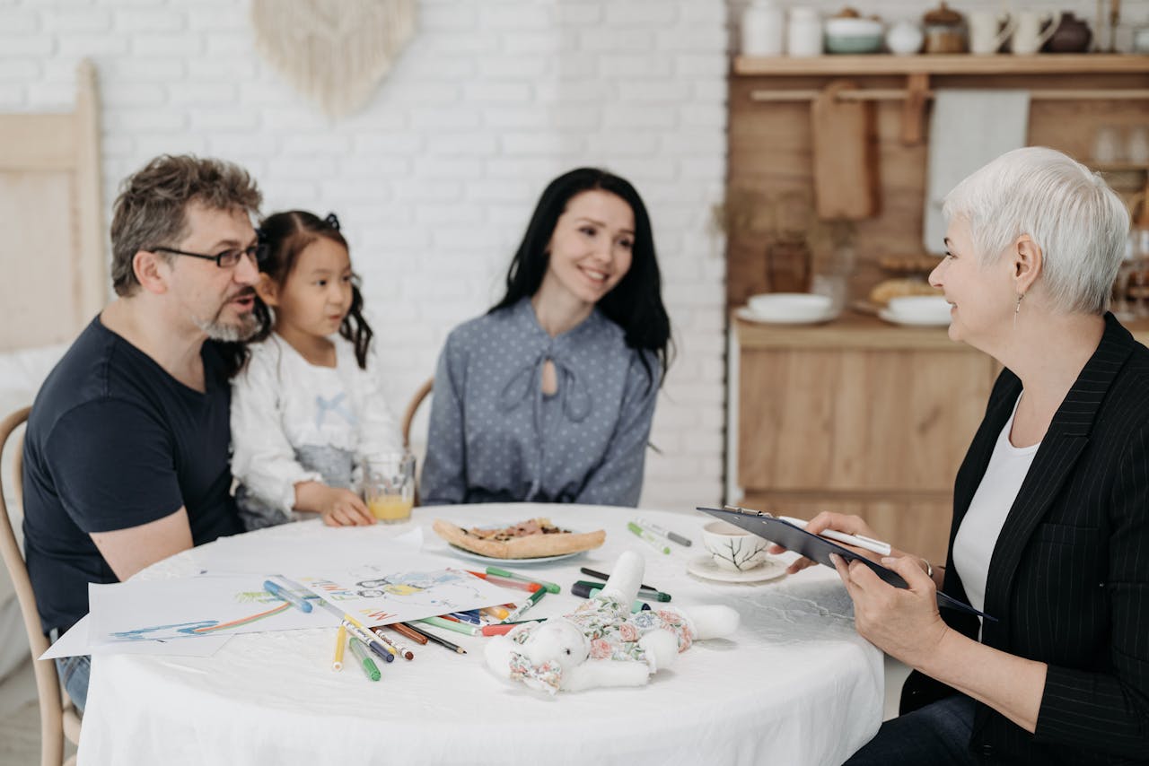 about-02 Adoptive family discussing with a social worker indoors, creating a warm, welcoming atmosphere.