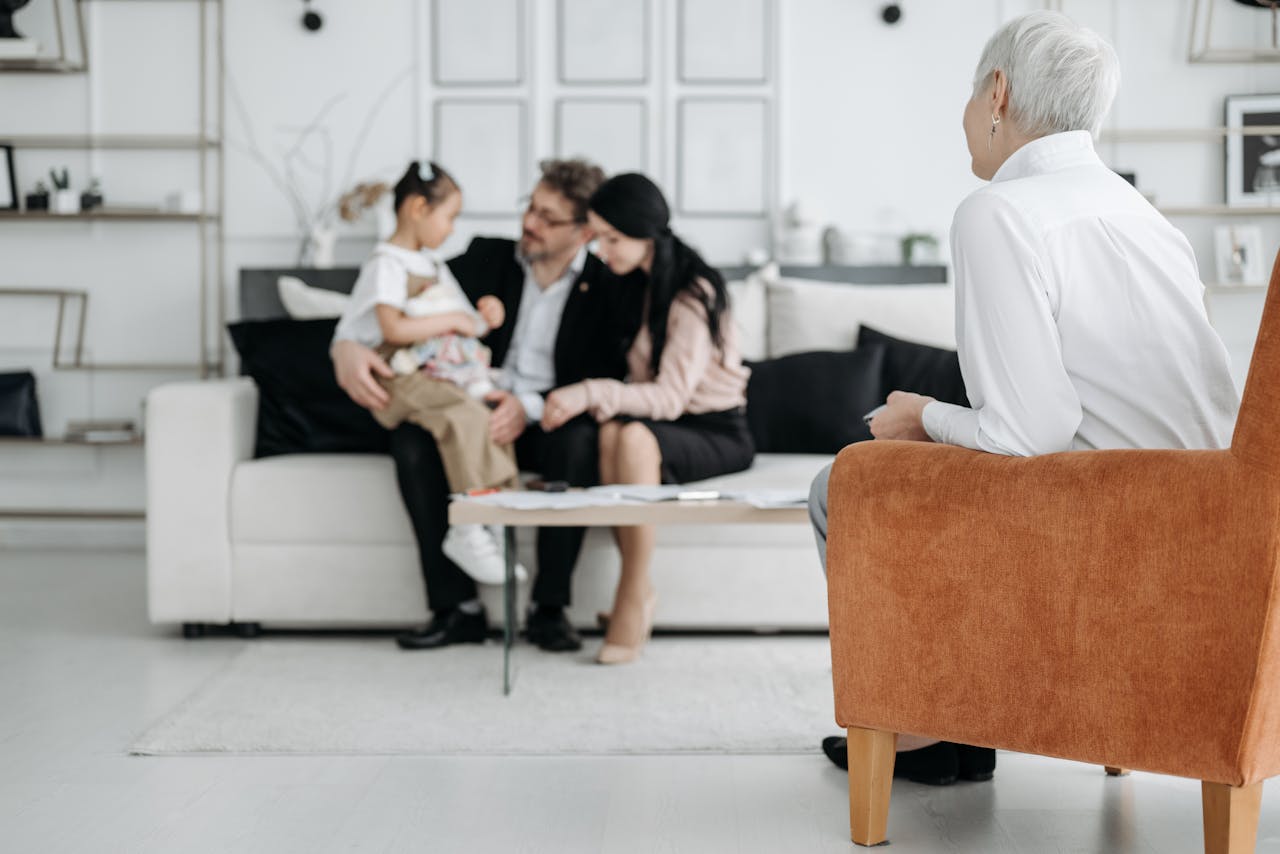 about-hero A joyful family adoption meeting with a social worker observing a couple embracing their new child.